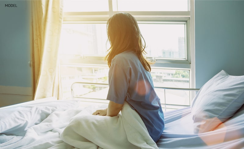 Woman sitting up in bed after relaxing during her recovery