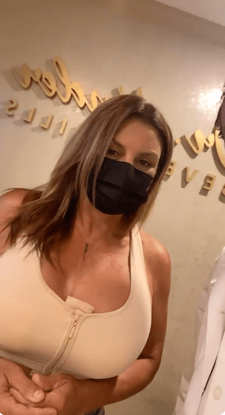 Woman wearing face mask and white sports bra in office.